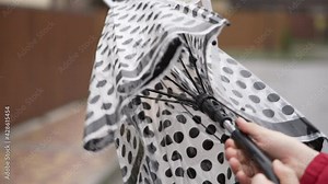 Rainy weather on the city streets. A man's hand opens an umbrella when it starts to rain.