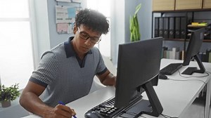 clip-3648192663-young-man-working-diligently-computer-bright-office