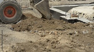 Mini excavator leveling the ground with the front bucket on the construction site