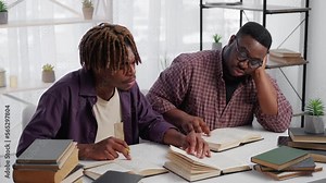 Home education. Male student. Preparing exam. Exhausted black men sitting desk studying books in light room interior.