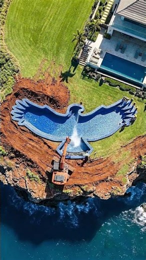 An eagle-shaped pool on the edge of a cliff at a luxurious seaside villa.