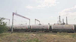 Download Rustavi, Georgia - 2025 - Freight train with Texol tanker wagons moves past large Rustavi industrial complex, with smokestacks, cooling towers, and visible environmental impact in background.