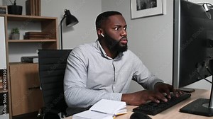 Shocked African-American guy staring on computer screen. A frustrated multiracial man surprised with bad news or unexpected occasions looks at monitor with eyes wide open