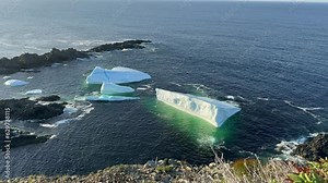 Massive frozen icebergs floating along iceberg alley off the coast of Newfoundland. The ice is melting in the deep blue ocean, a sign of global warming and a change in the environment.