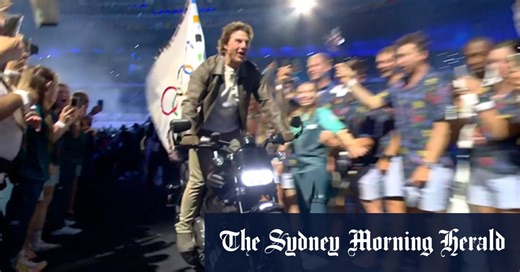 Tom Cruise rides motorbike with Olympic flag out of closing ceremony