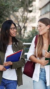 Happy College student girl friends talking and walking to University School. Diverse Asian and American Youth