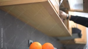a man opens the kitchen unit to take and put back a stemware