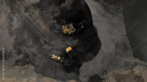 Coal mining in an open pit. Wheel loader loads coal in haul truck in quarry. Mining excavator digging in an open pit coal mine. Tipper truck hauling ore from open-pit. Heavy machinery in opencast.