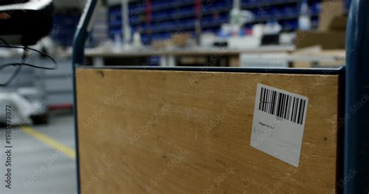 Close-up of hand using a handheld barcode scanner with laser on a cardboard box in a warehouse