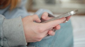 Side view. Hand of girl using smartphone in the living room at home, typing message. Close-up of young women hand Generative AI