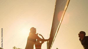 SLOW MOTION, LOW ANGLE, CLOSE UP, LENS FLARE: Athletic Caucasian woman in bikini spikes the ball past the jumping man and scores a point in volleyball. Fit people playing beach volleyball at sunset.