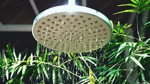 Close up Open shower with fresh water in slow motion on background of beautiful bamboo garden