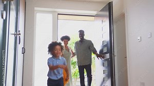 Excited children running through front door into hallway of house with parents behind as family return from trip out - shot in slow motion