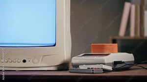 Old television with blue interference screen on home background. Close-up of vintage tv and cartridges for retro playstation. Antique video game, nostalgia.