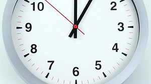 Close-up view of white clock with black numbers The second hand moves around the dial.