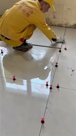 A worker carefully aligns levels floor tiles using spacers to ensure even gaps and a smooth surface