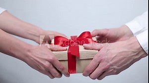 Female and male hands give a box with a gift. Holiday packaging.