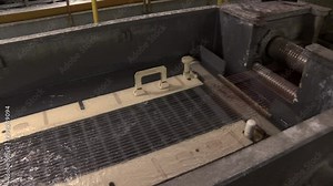 Production of wire by drawing technology. Wires pass through sulfuric acid. Wire production line by drawing method. A thin wire is drawn through a container of liquid.