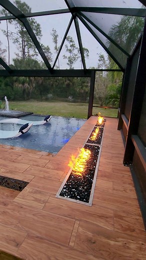 We design and build some insane modern pools. This backyard features an elevated sun shelf with ledge loungers, a swim-up bar, fire features, an outdoor kitchen, a sunken living area, a fountain wall, and a screened enclosure. #insanepools #lucaslagoons #modern | Lucas Lagoons