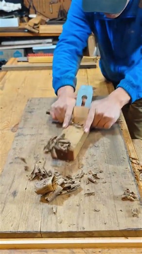 smoothing and leveling a large old wooden board with a manual hand plane tool on a workbench