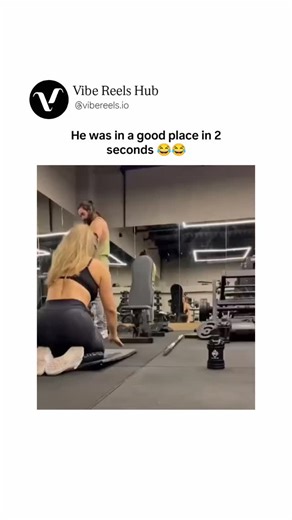 Vibe Reels Hub™ on Instagram: "The video takes place in a modern gym with mirrored walls, weight machines, and rubber flooring, where a fit woman with long blonde hair, wearing a black sports bra and leggings, lies face down on a blue mat in a plank-like position with her hips elevated for a deep stretch. A muscular man with long dark hair and a beard, dressed in a green tank top and gray sweatpants, approaches her from behind, picking up a long metal barbell pole from the floor. He carefully po