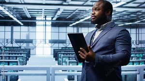 Programmer in server room location using tablet to patch network issues affecting transfer rates. African american man in data center fixing errors affecting mainframes, camera B