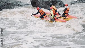 Rafting team descending raging rapids in mountain river with paddles splashing in water in slow motion. Close-up