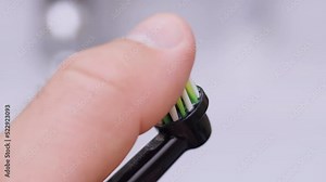 Worn out bristles of electric toothbrush. View of old ultrasonic tooth brush head in bathroom. Finger strokes smart black toothbrush with colorful bristles for oral hygiene and cavity prevention.