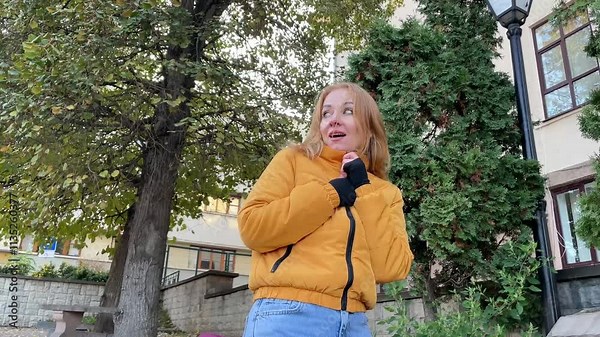 Woman shivers in the cold outdoors, showcasing the chill of winter with a smile despite the freezing temperatures
