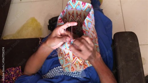 Hands of a Wayuu woman from La Guajira, North Colombia, skillfully weave a traditional Wayuu mochila. Bright colorful patterns reflect the tribe’s cultural artistry- iconic Colombian folk handicraft.