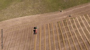 Top-down Shot Of A Farm Machinery Baling A Row Of Hay At The Field In Saskatchewan, Canada - aerial