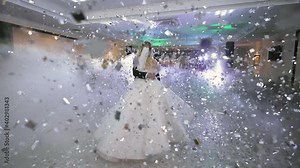 beautiful blond bride and handsome groom dancing first dance at the wedding party. Confetti in the air. Very tender moment