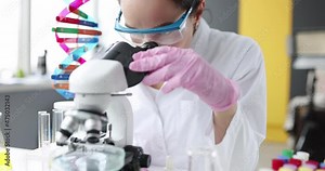 Young woman doctor scientist working with test tubes on microscope