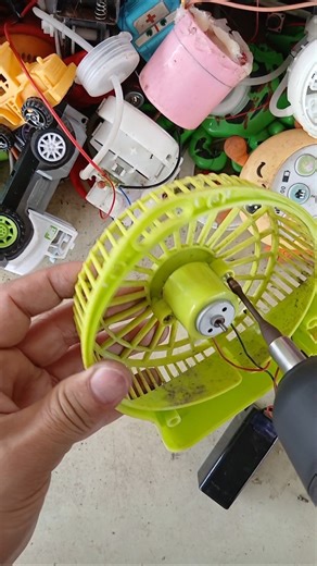A broken light blue mini fan was found in a pile of old things.