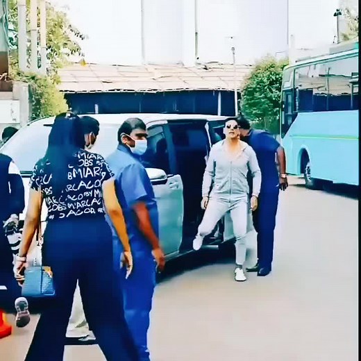 Confident Man in Gray Tracksuit Approaches Blue Bus