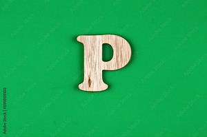 A light beige wooden letter "P" is positioned against a bright, solid green surface.