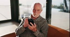 Scroll, mobile and senior man on sofa for puzzle game, memory test or health website in living room. Online, relax and elderly person for browsing internet, reading ebook or retirement in home