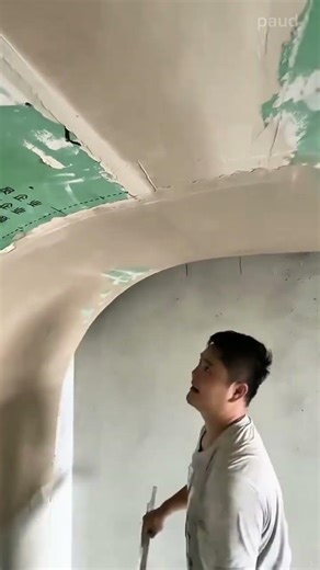 Applying smooth plaster to a curved interior archway with a large metal trowel and precise skill