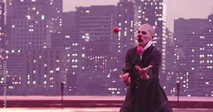 Mime or clown juggling red balls in the background of the modern city skyline at night.