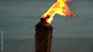 Flame form tiki torch at sunset in slow motion. Vacation and travel concept.