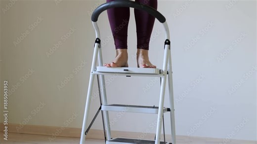 Woman is standing on a step ladder. She is wearing purple pants. The ladder is white