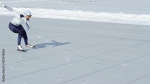 Determined female speed skater in racing suit and protective goggles sprinting along track on outdoor ice rink