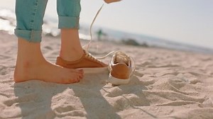 close up feet woman walking on beach taking off shoes enjoying warm soft sand exploring summer vacation lifestyle