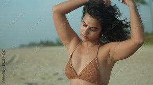 Woman in bikini enjoying sun on tropical beach, shallow focus, candid