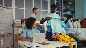Volunteers sorting clothes at nonprofit charity organization, packing into boxes