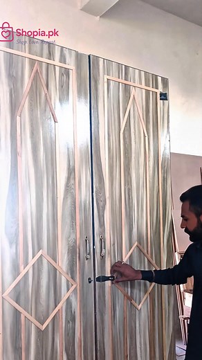 Double-door wooden wardrobe with a gray wood grain finish and light geometric trim.  Whatsapp: 03290021100  Site: shopia-pk #trending #reels #viral #WoodenWardrobe #WoodFurniture #Cabinetry #GeometricDesign #HomeStorage #InteriorDecor # | Shopia.pk | Facebook