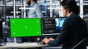 Data center programmer using green screen PC monitor, using AI. Man in tech startup office using artificial intelligence on chroma key computer to oversee servers powering deep learning, camera A