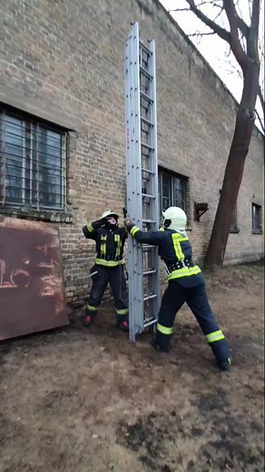 Firefighters Extending Ladder Against Brick Wall