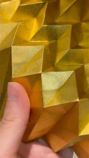 Folding gold paper into geometric forms. Origami; Illusion(Gold)