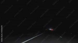 Windshield view of dark unlit highway while driving on the left hand side of a road at night in England, United Kingdom